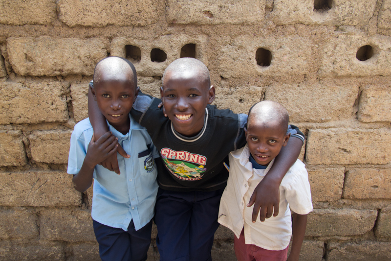 Three young boys smiling with their arms around each other.
